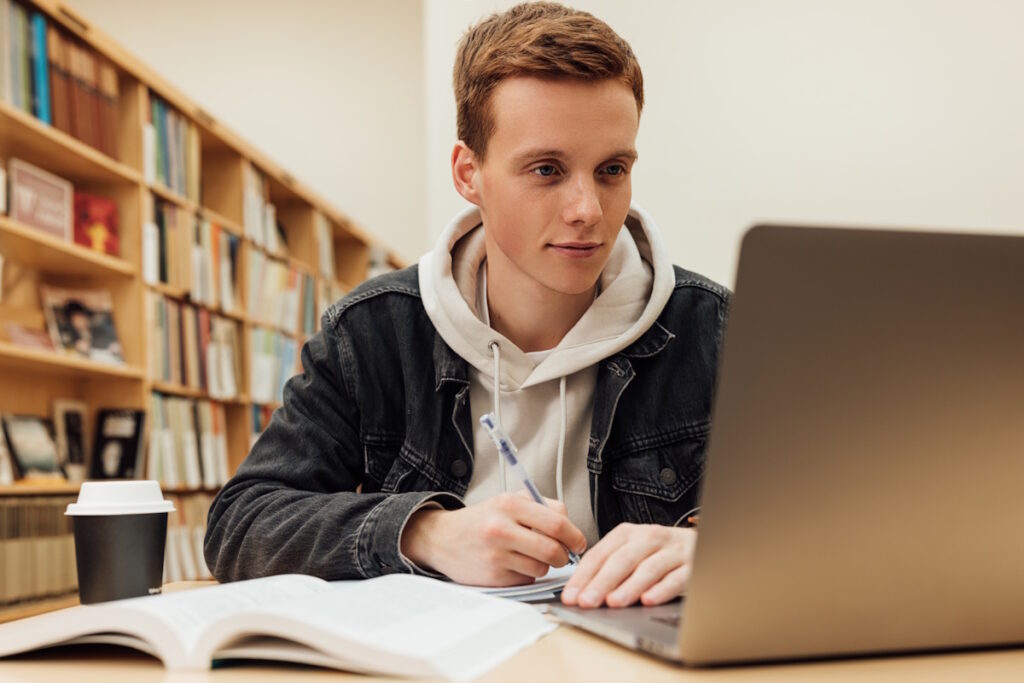 Étudiant souriant travaillant sur un pc portable
